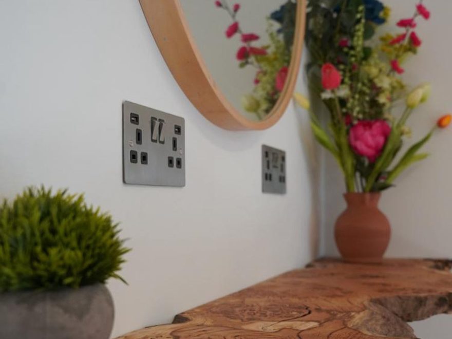 The clinic interior: a live-edge wooden console, a round mirror and fresh flowers